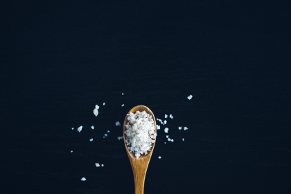 A wooden spoon overflowing with salt 
